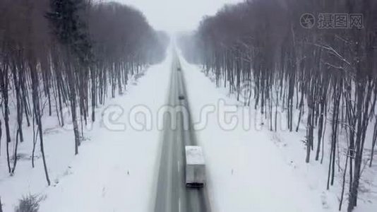 降雪时被冬季森林包围的道路上的交通鸟瞰图视频