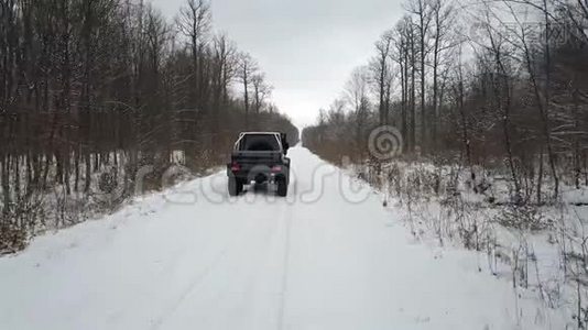 从空中观看越野车6x6，在冬天的森林里骑在白雪覆盖的道路上，后景视频