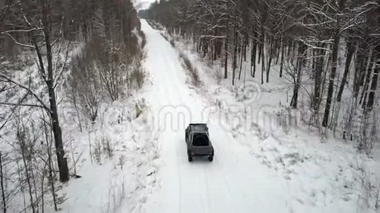 从空中观看越野车6x6，在冬天的森林里骑在白雪覆盖的道路上，后景视频