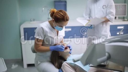 女牙医检查病人的女孩牙齿。 牙科诊所的牙科医生，带镜子检查病人的女牙视频