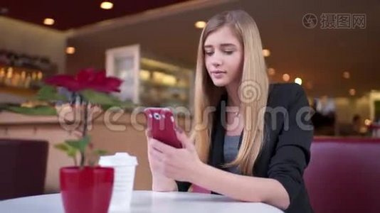美丽的女人坐在咖啡馆里，A©和一个朋友在她的智能手机上发短信。 她对她的回答感到惊讶视频