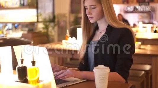 穿着黑色夹克的金发女孩坐在咖啡馆A©里。 4.她专心致志地工作视频