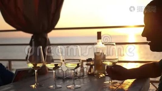 日落时分，两个朋友正坐在海边的一家餐馆里，喝着酒。 高清，1920x1080。 慢动作视频
