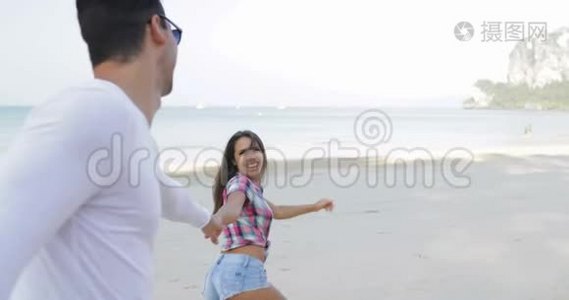 女人牵着男人的双手在沙滩上奔跑，年轻的快乐游客在度假视频
