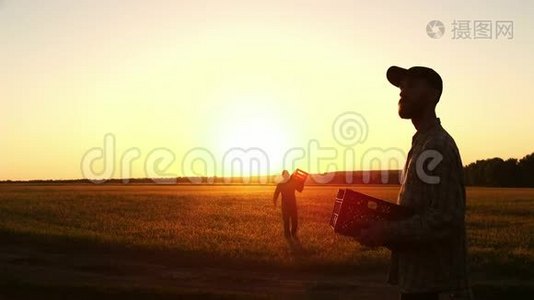 日落时，两个农民在一个木箱里一起搬运玉米。视频