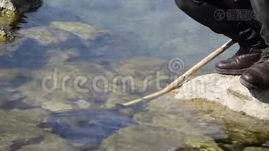 海岩上的人用渔网在水中的低视角视频