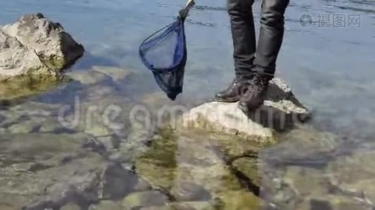 海岩上的人用渔网在水中的低视角视频