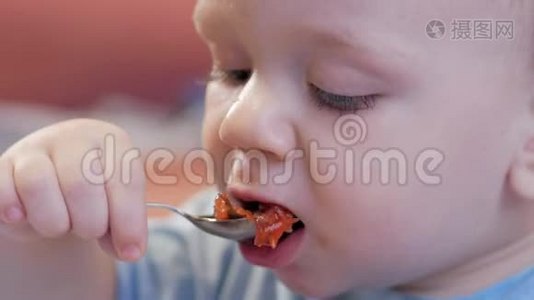 一个2岁有魅力的男孩自己在吃红汤。 贝叶夹在盘子里，孩子玩它。视频