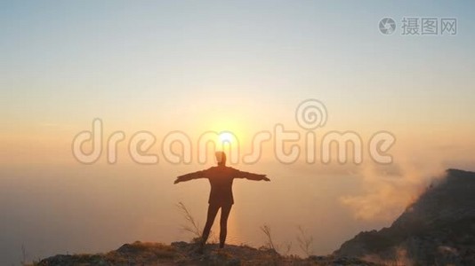 在克里米亚的一座高山上，年轻女子伸出双臂，在海面上观看一场美丽的戏剧性日落视频