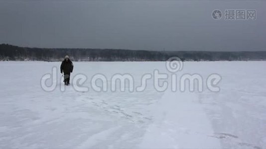 一个背着背包在冰冻的河面暴风雪中行走的人视频