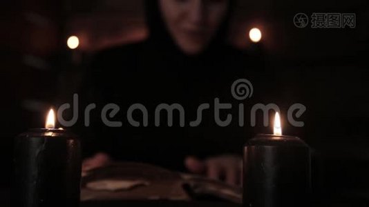 神秘美丽的修女穿着黑色的裙子，修女读着一本带有黑色烛光的旧书视频