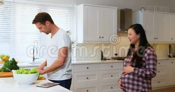 孕妇在切菜时与男子交谈视频