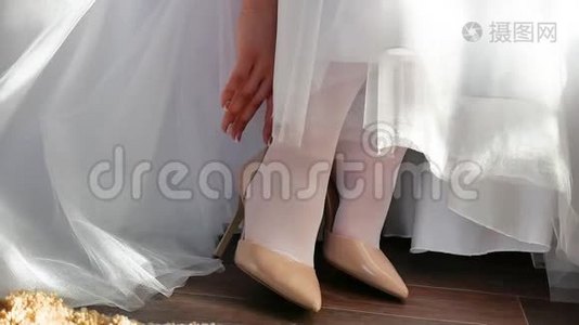 穿着白色连衣裙的新娘穿上鞋子来伸直手指。 婚礼概念节日室内生活视频