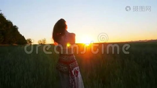 年轻女子在日出时快乐地跑过绿色的田野，慢动作视频