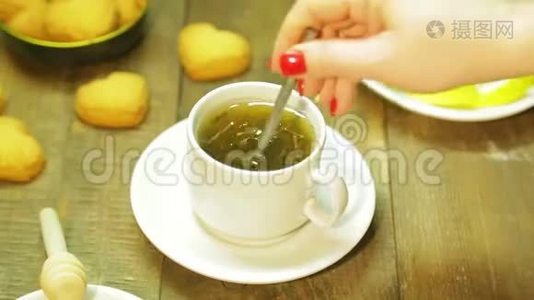 女人在木桌上的白色杯子里搅拌勺子。 新鲜绿茶视频