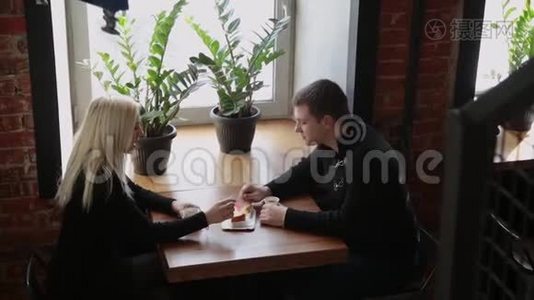爱情夫妻坐在咖啡馆里吃甜点，喝咖啡，互相看着。视频