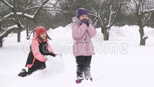 快乐的孩子们在雪地里玩耍的慢动作。 两个快乐的女孩在冬天外面玩视频