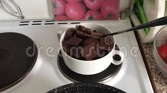 在炉子上的碗里放了一块黑白巧克力。 巧克力被融化在水浴中做甜点。视频