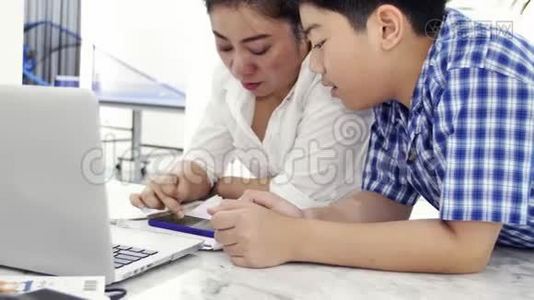母亲和儿子玩和看智能手机，多莉拍摄了快乐的亚洲家庭在家的笑脸。视频