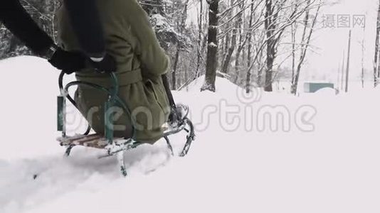 在阳光明媚的冬日里，年轻的夫妇滑着雪橇，享受着快乐。 慢动作视频