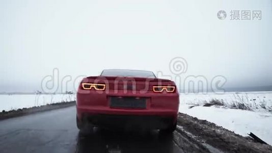 红色跑车开始在被雪覆盖的田野包围的道路上行驶视频