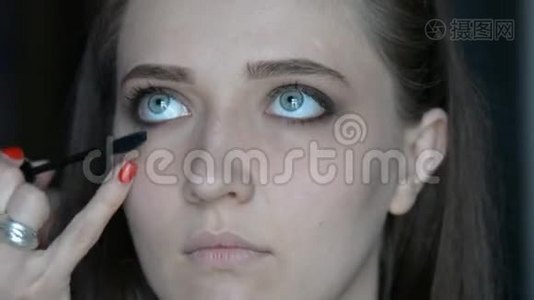 特写化妆师在模特儿的眼睛和眉毛上化妆`绿色文印上一个红色成熟番茄的化妆马克罗形象视频