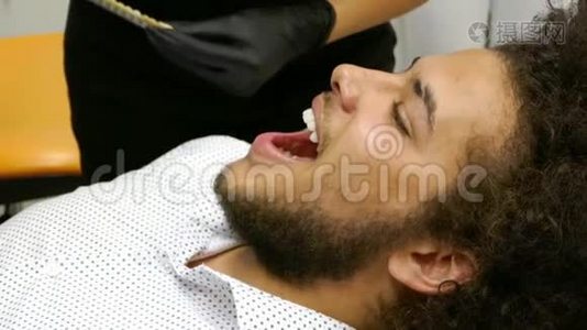一位病人坐在牙医的椅子上，等待牙医确定他牙齿的正确颜色视频