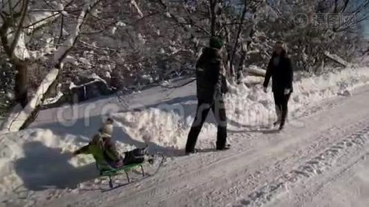 年轻的幸福家庭在雪林里玩得很开心。 父母把他们的小儿子卷在雪橇上。 慢动作。视频