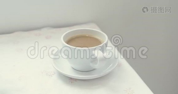 近距离观看女性手拿一个白色杯子与热咖啡从桌子上。视频