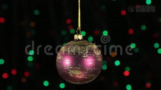 红色圣诞球摆动在离焦背景与闪烁的花环灯。视频