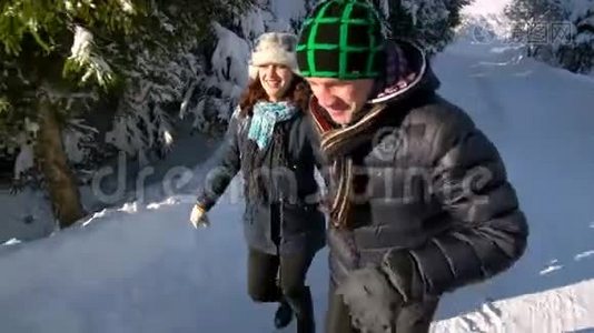 年轻的幸福家庭在雪林里玩得很开心。 父母把他们的小儿子卷在雪橇上。 慢动作。视频