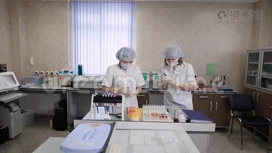 两名穿着白大褂的护士在检查试管时对病人进行血液测试，以便在显微镜下或放置玻璃视频