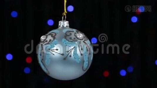 蓝色圣诞球摆动在离焦背景与闪烁的花环灯。视频