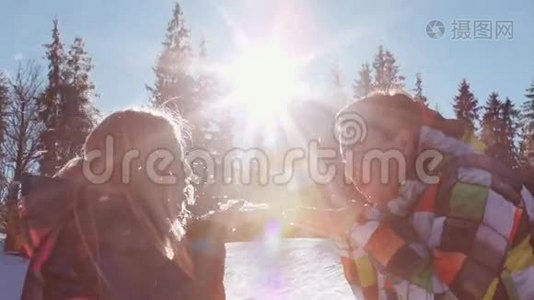 可爱的年轻夫妇穿着冬季运动服。 阳光明媚的冬日，快乐的金发女孩和男孩互相吹雪视频