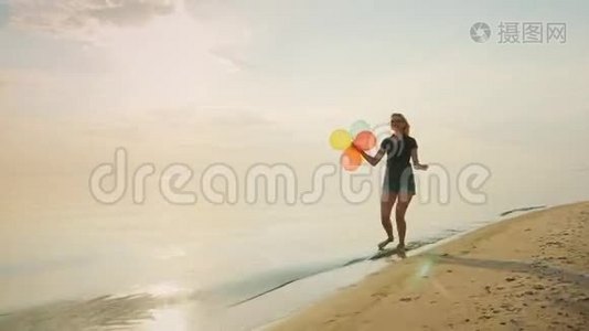 无忧无虑的年轻女人在海滩上奔跑，手里拿着气球。 概念-安逸，自由，快乐，视频