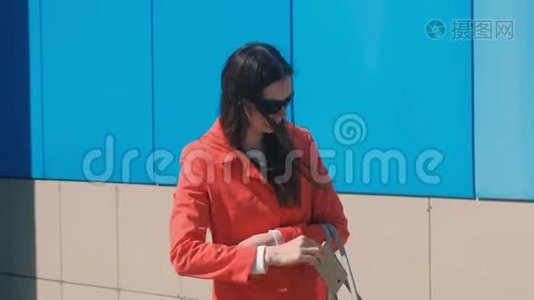穿着红色外套戴墨镜的年轻女人在等人，检查她的手机，发短信。视频