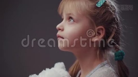 可爱的金发女婴，一双蓝色的大眼睛，抱着她最喜欢的玩具-白色泰迪熊，看着远处，然后转过身来视频