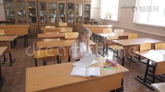 小女孩坐在学校的班级里学习。视频