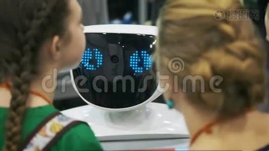 一个白色机器人在一个新技术的展览上与一个小学生互动。 这孩子熟悉视频