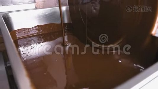 巧克力回火机中的温液巧克力。 特写镜头。 巧克力糖果的生产。视频