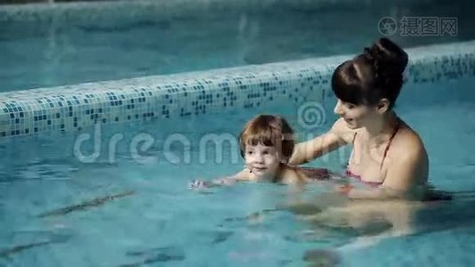在游泳池里的母子。 年轻的母亲教她3岁的儿子游泳视频