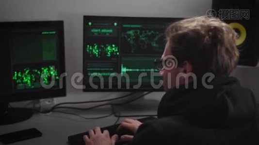 戴眼镜的严肃男人，穿着带罩的黑色夹克，坐在电脑前，正在为视频