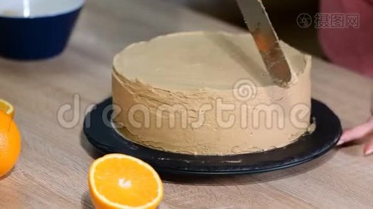 糖果师把奶油放在蛋糕的顶部。 面包师平滑蛋糕与奶油糖霜。视频