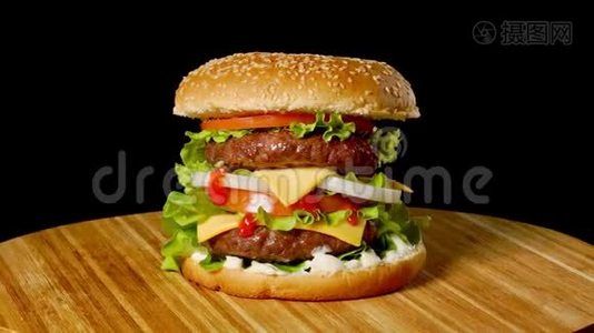 大汉堡配牛肉、西红柿、蘑菇和黄瓜，配上融化的奶酪，在黑色的木板上旋转视频