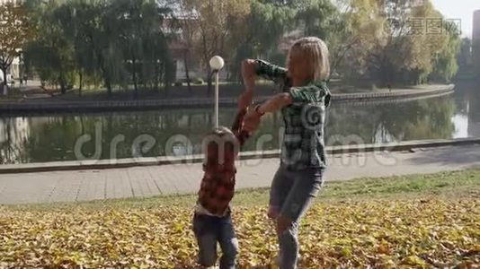 年轻的母亲和儿子在阳光明媚的秋天公园玩视频