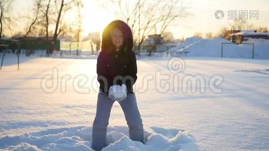 一个女孩把雪扔到头上，落在夕阳背景下的雪上视频