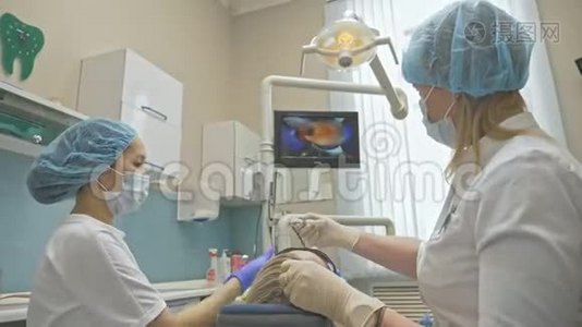 医生用特殊的口腔检查数字微相机检查牙齿。 监控牙医和病人看录像视频