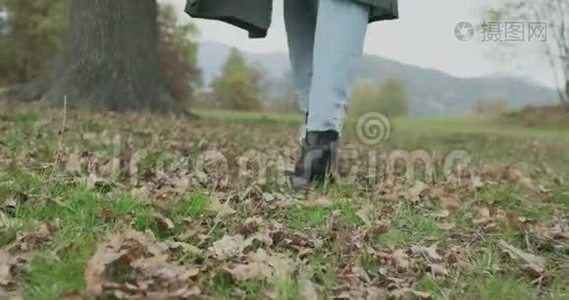 关于鞋子和台阶的细节。 白人金发女人斯洛莫走向秋天的树林，触摸树。 在万向节后面视频