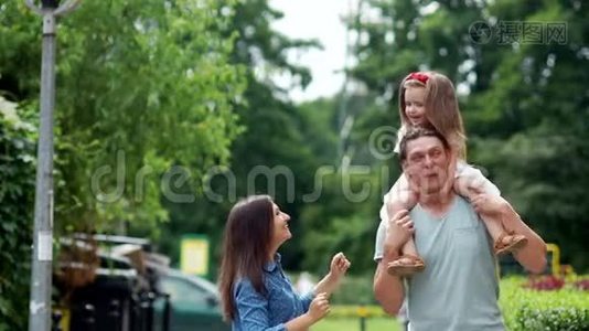 家人的吻。 妈妈，爸爸和小女儿在城市公园里走来走去。视频