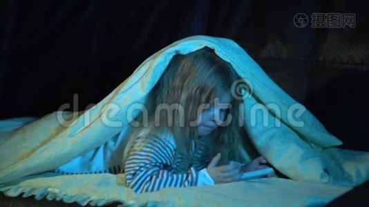 一个晚上穿着条纹睡衣的小女孩在房间里用智能手机视频